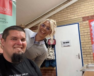 Jonny smiling with the barber before having his renowned beard shaved off at the Great Shave Off fundraiser.