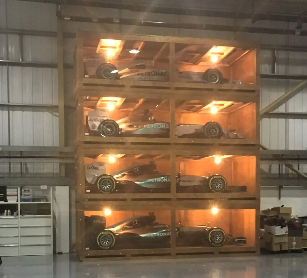 Bespoke stackable display cases with perspex windows and integrated lighting showcasing Formula One cars, designed for reusable export packing and optimised logistics efficiency.