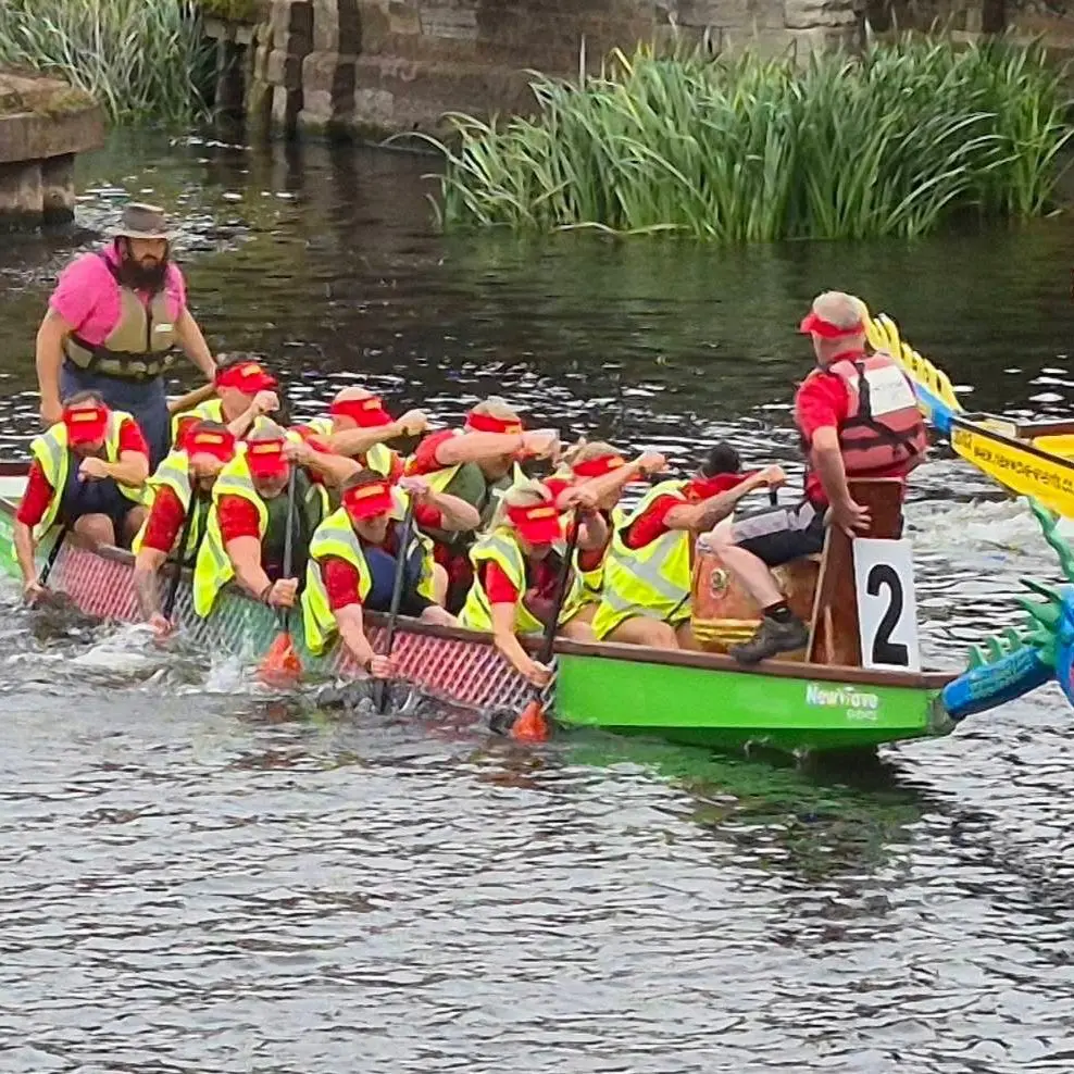 International Export Packers crew paddling in a dragon boat during the Newark Dragon Boat Festival, showcasing teamwork and community spirit.