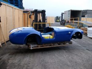 A car securely packed inside a shipping container using a custom-built timber frame and straps to ensure safe transport by cargo ship.